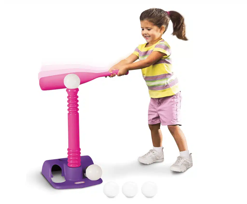 A girl in ponytail swinging a ball with a pink and purpler T-ball set
