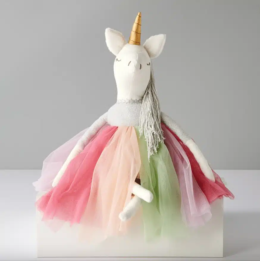 A sitting unicorn doll with golden horn and colorful skirt