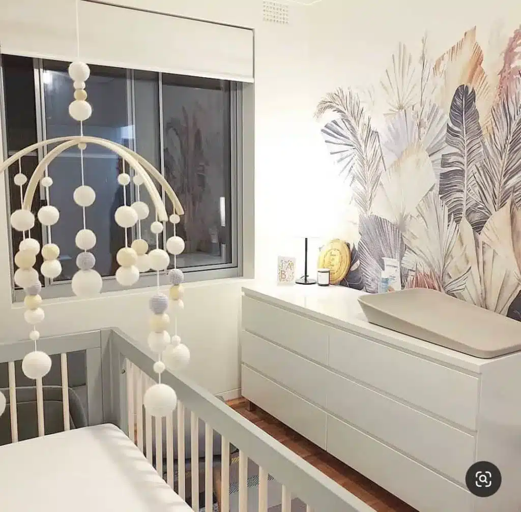 Boho garden gender-neutral nursery with leaf mural and white crib