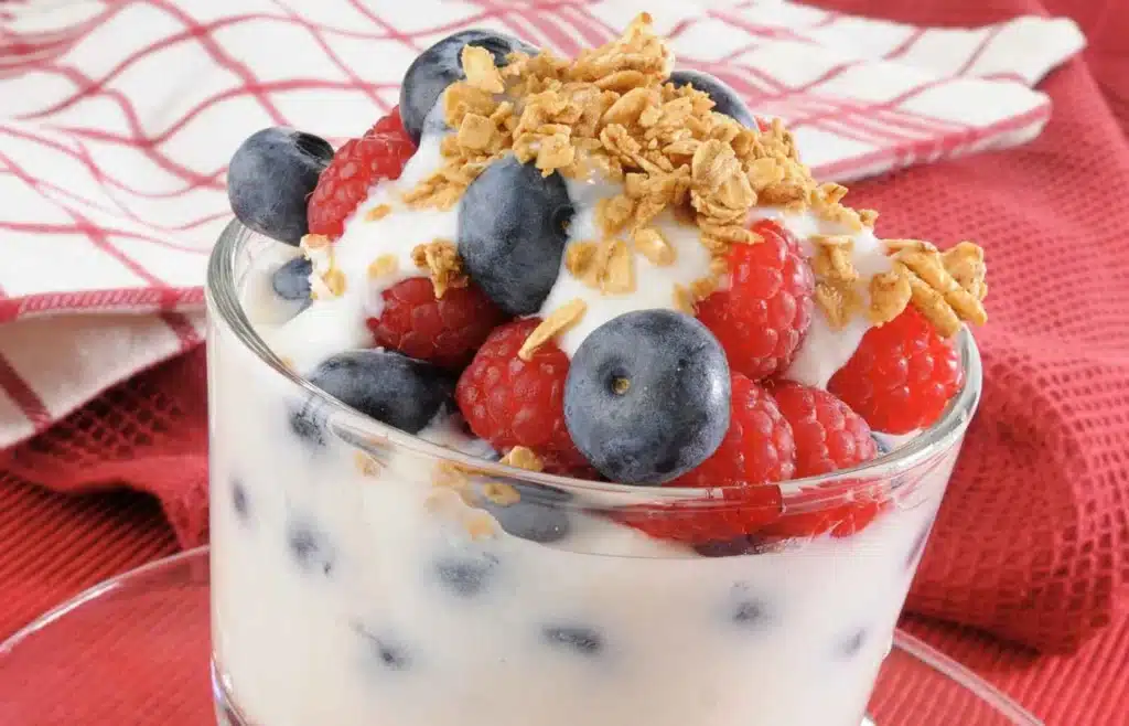 Greek yogurt parfait with berries and granola in a glass cup.