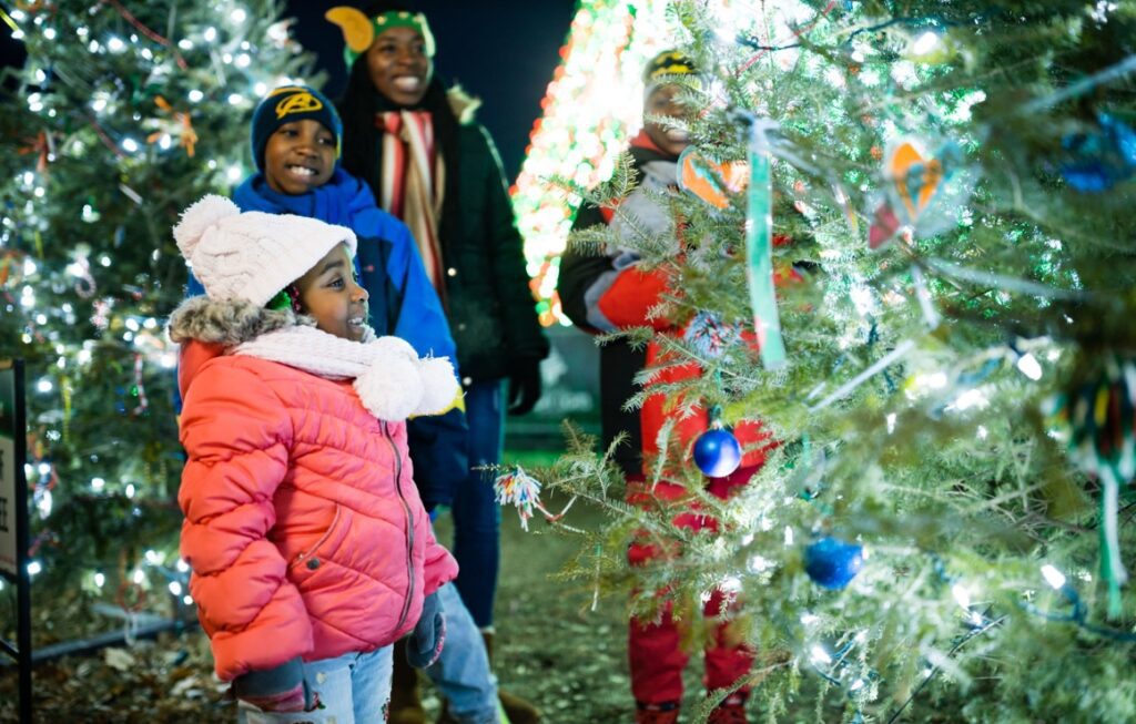 A family of four enjoying the lighted Christmas tree designs at Cathedral Square Park