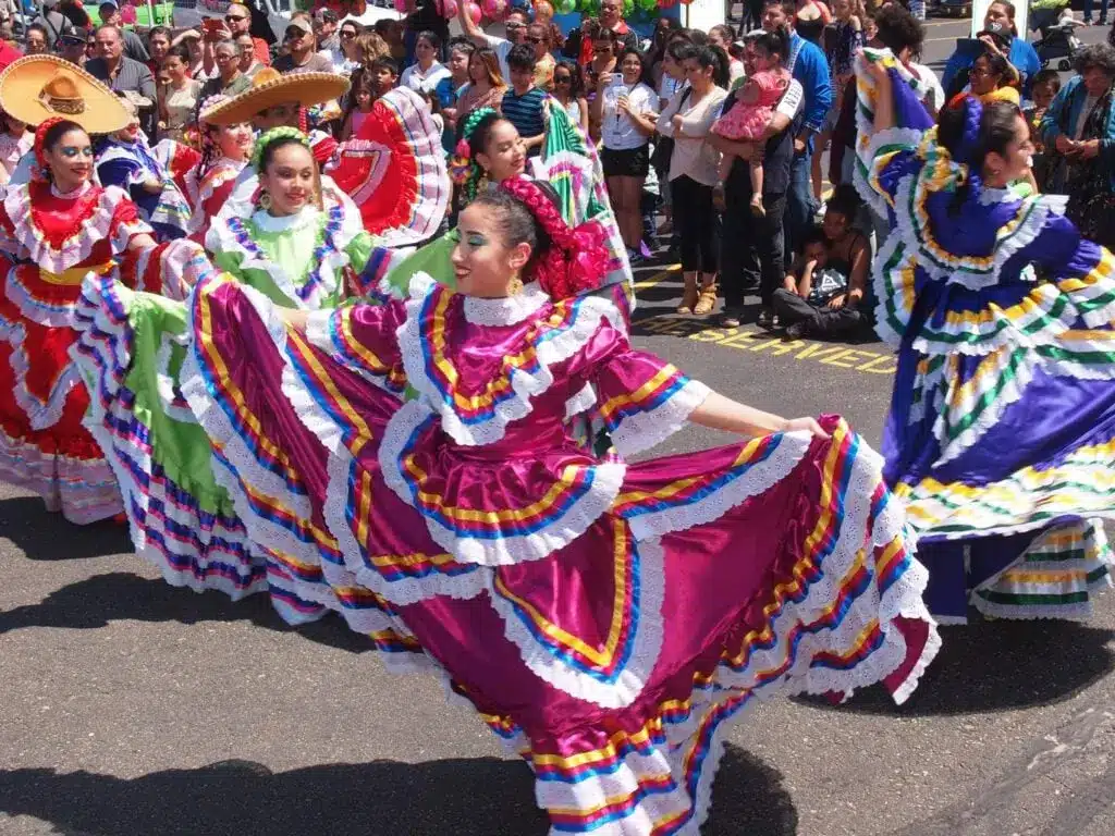 Girls in coloful Cinco de Mayo costumes dancing on the streets