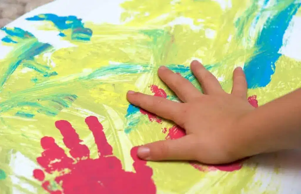 An artwork using blue, yellow and green with two handmarks made of red paint