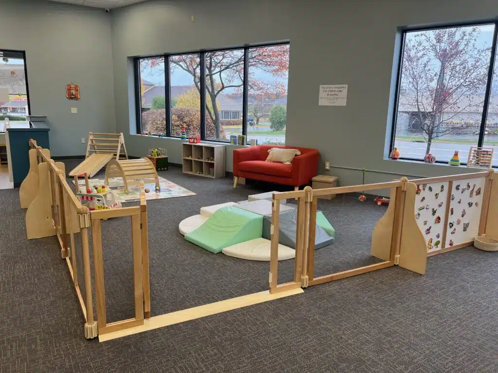 Soft baby play area with wooden climbers, toys, and cozy seating at Bug & Goose Delafield.
