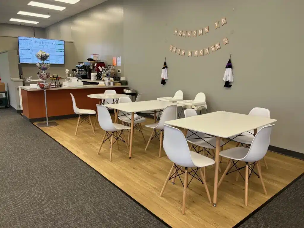 Café seating area with tables, chairs, and espresso bar inside Bug & Goose Delafield.