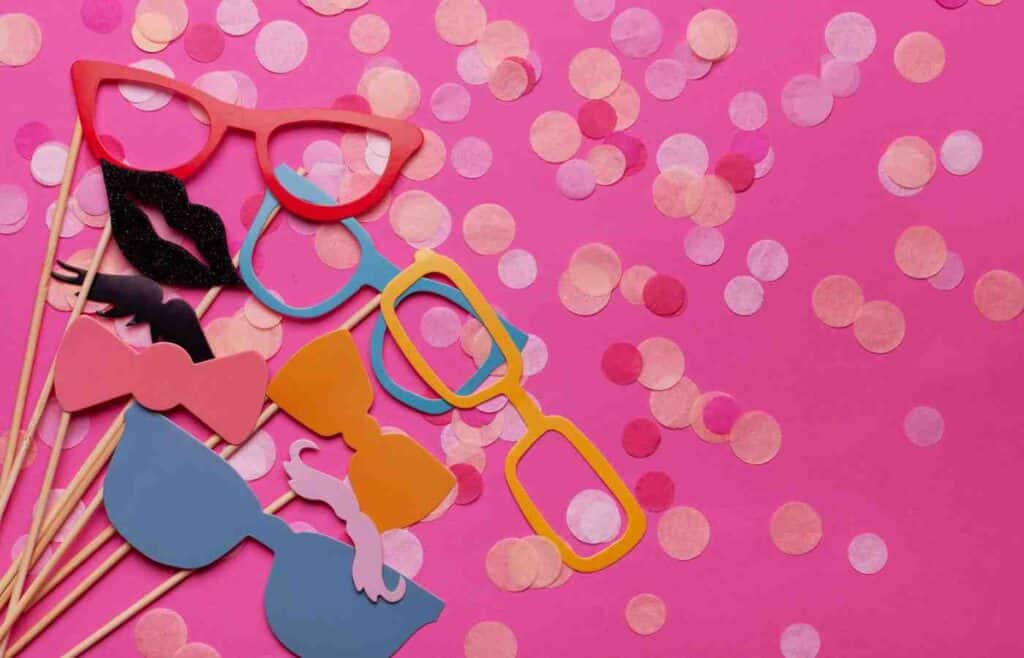 Different eye glass props on stick anc pinkconfetti on pink background