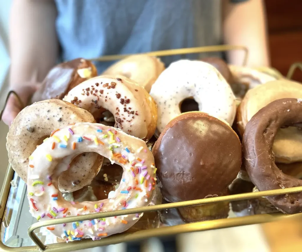 A tray of assorted donuts from Donut Monster in Milwaukee, featuring frosted, sprinkled, and chocolate-glazed flavors.