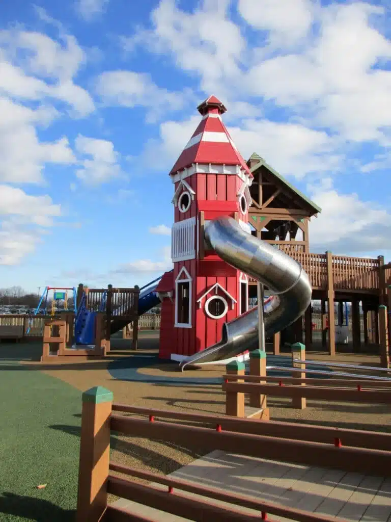 Red lighthouse play structure with metal slide at Dream Playground in Kenosha.