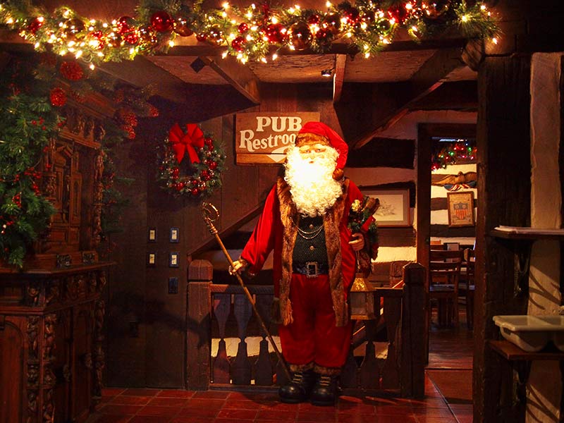 Santa statue holding a cane and lamp beside a staircase