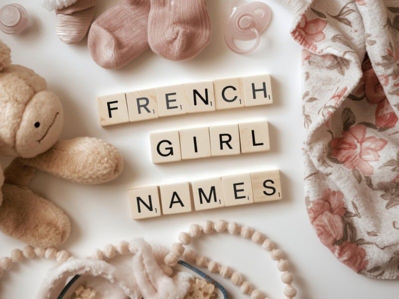 Flat lay design with pink socks, printed pink blanket, pastel brown teddy and wood block spelling of French Girl Names
