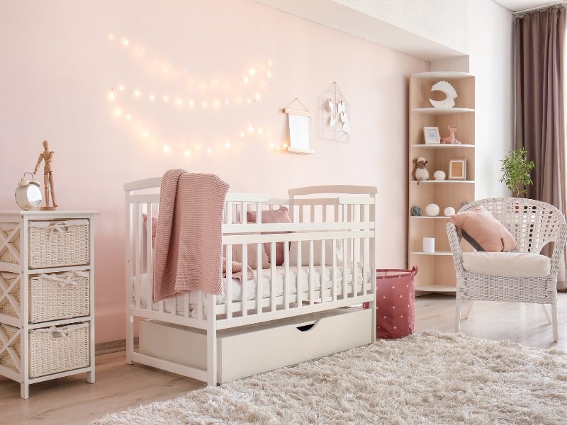 A minimalist nursey with soft pink walls and white crib to symbolilze modern French girl names