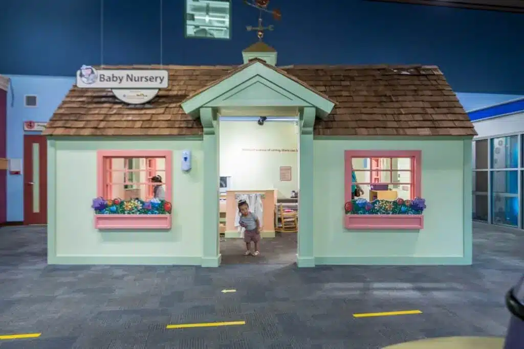 A pastel-colored play house with young children playing inside