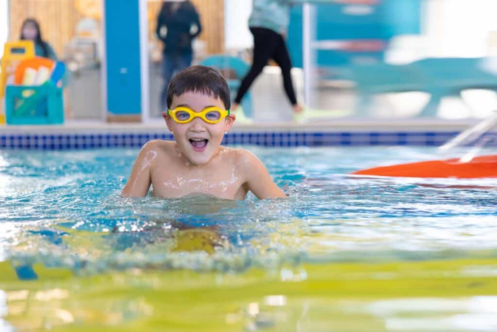 A boy with yellow goggles is practicing his breast stroke techniques