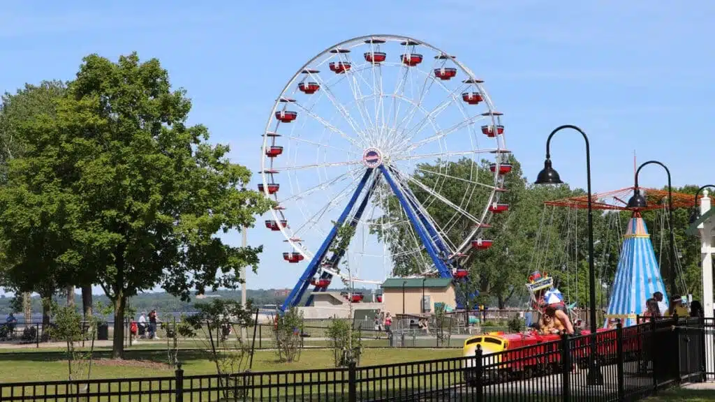 The Big Wheel Ferris wheel at Bay Beach Amusement Park with red gondolas, trees, and families 