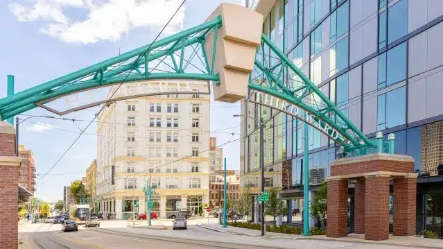 Historic Third Ward Milwaukee neighborhood entrance arch with streetcar tracks, shops, and modern city buildings.