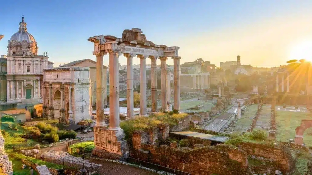 Roman Forum ruins with tall columns glowing in sunrise light.
