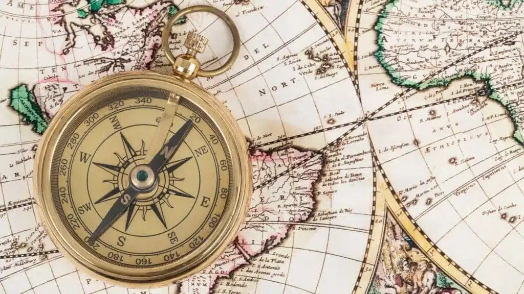 Brass compass resting on an antique world map.