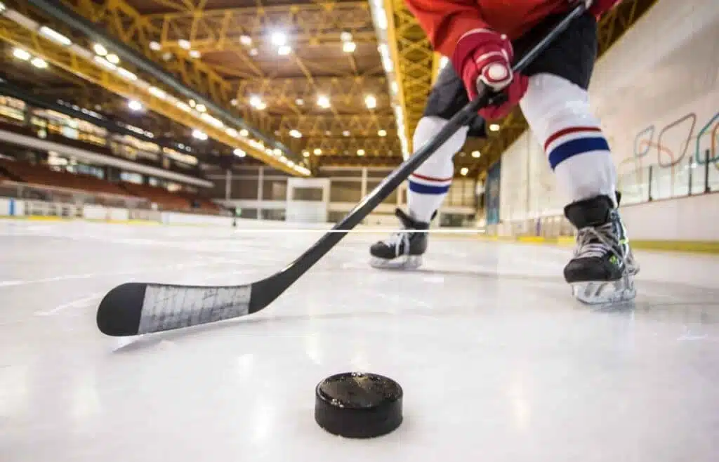 A hockey player is practicing how to control the puck and stick on the ice rink.
