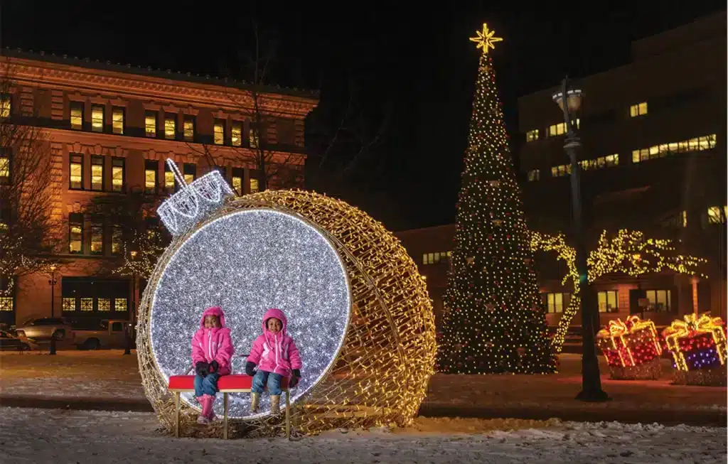 Girls in pink jacket posing for  photos at one of the holiday lights displays at the Milwaukee Holiday Lights Festival.