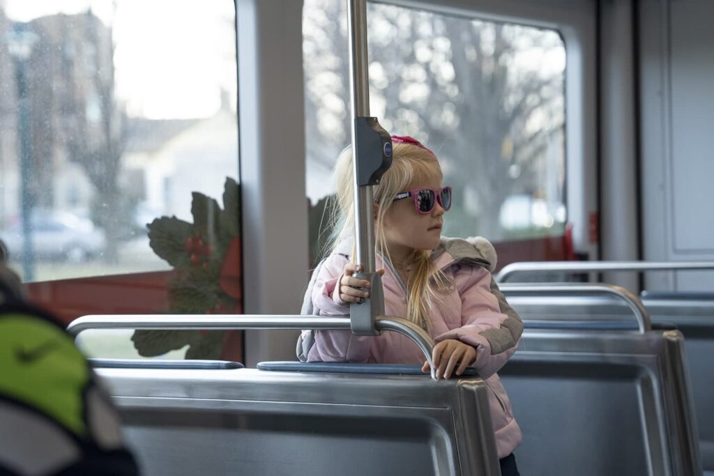A girl with pink jacket and sunglasses riding a street car during the Holidays on The Hop in Milwaukee.