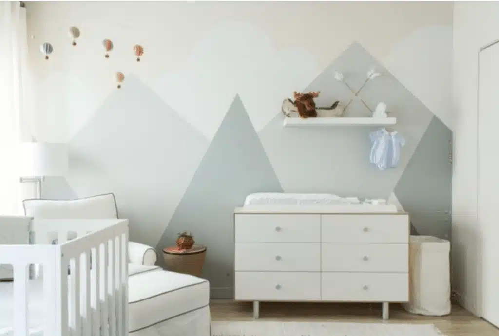 Hot air balloon gender-neutral nursery with geometric wall mural and white dresser