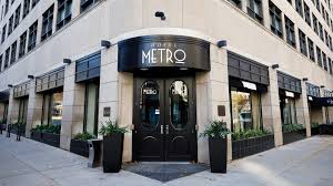 View of the entrance of Hotel Metro with black door and potted plants on the side