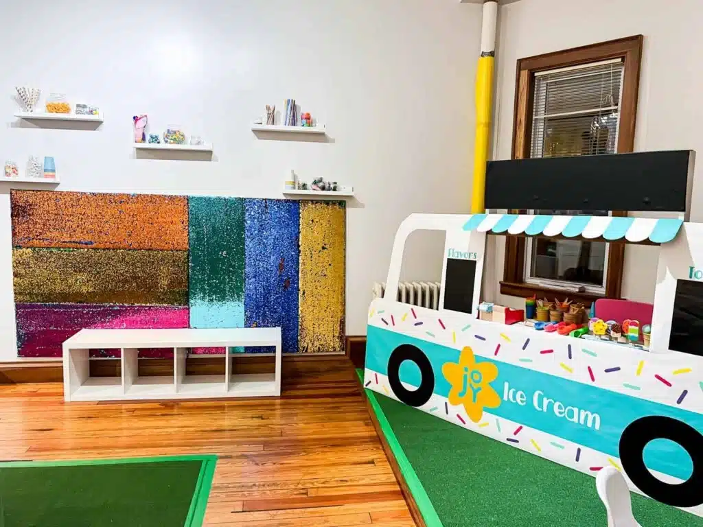 A play area featuring ice cream truck setup and colorful sensory wall.
