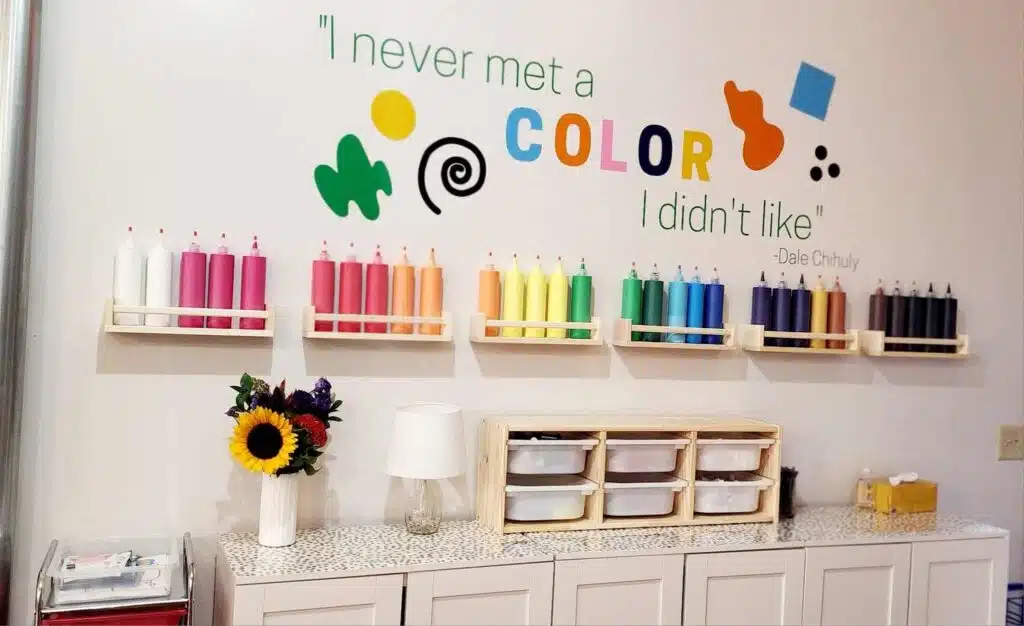 Paint bottles displayed beneath colorful quote wall 