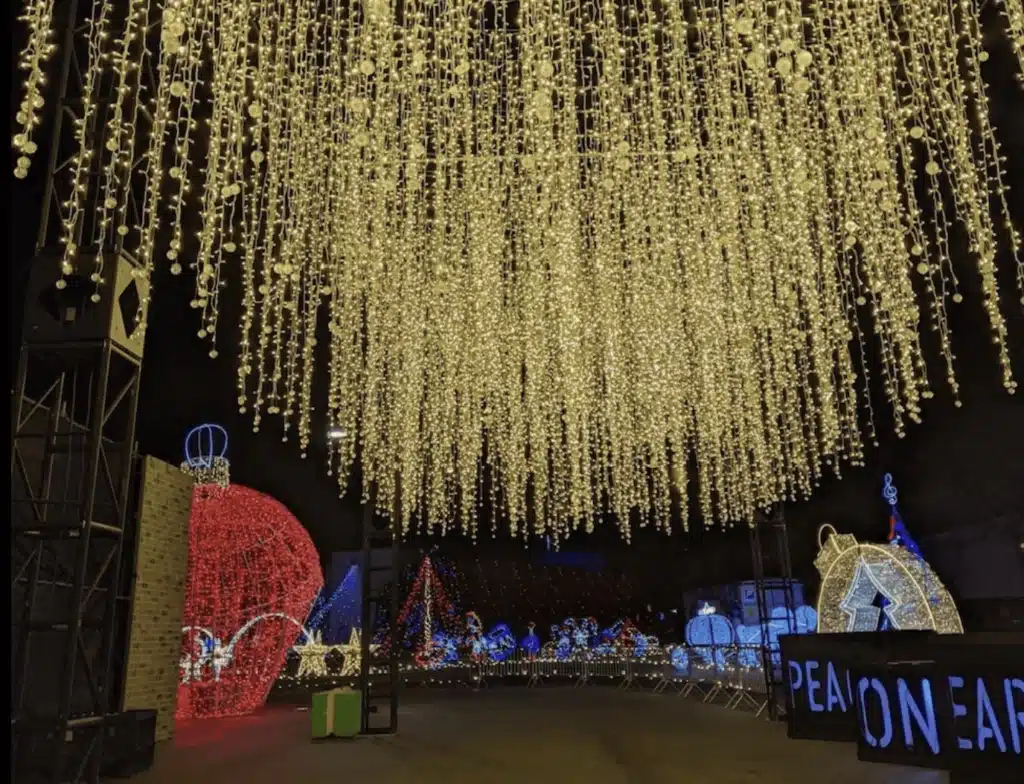 A large Christmas lights display featuring giant Christmas balls and a large sign that says Peace on Earth