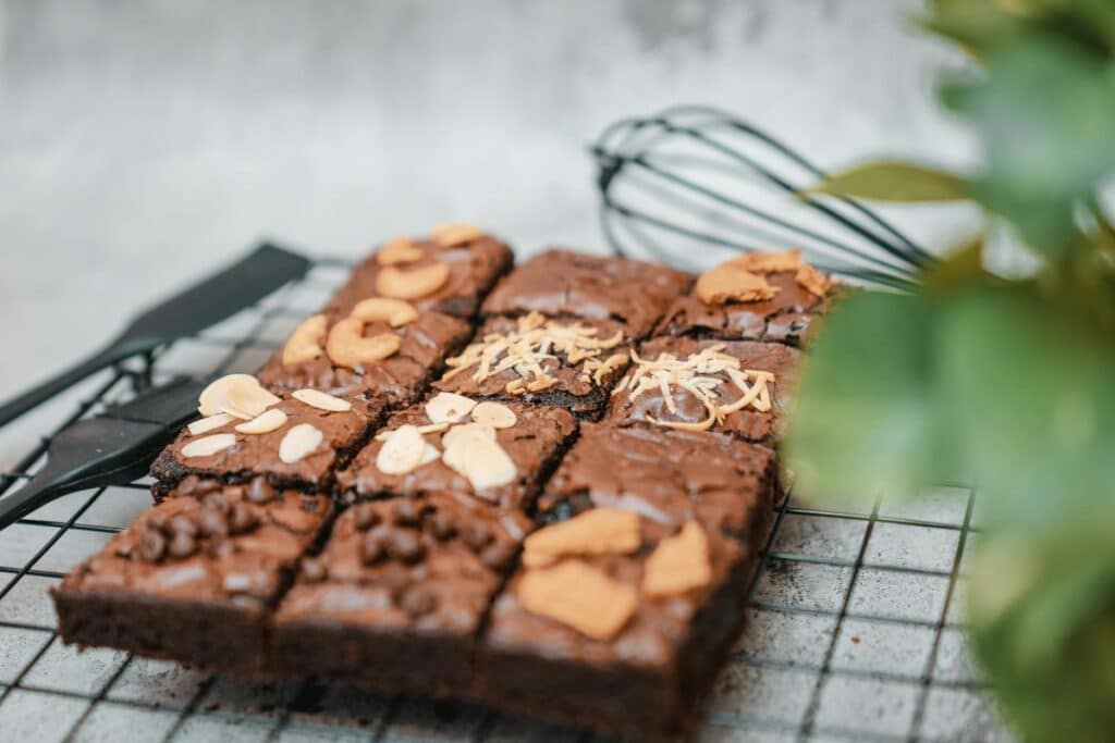 Brownie squares topped with chocolate bits and nuts placed on rack