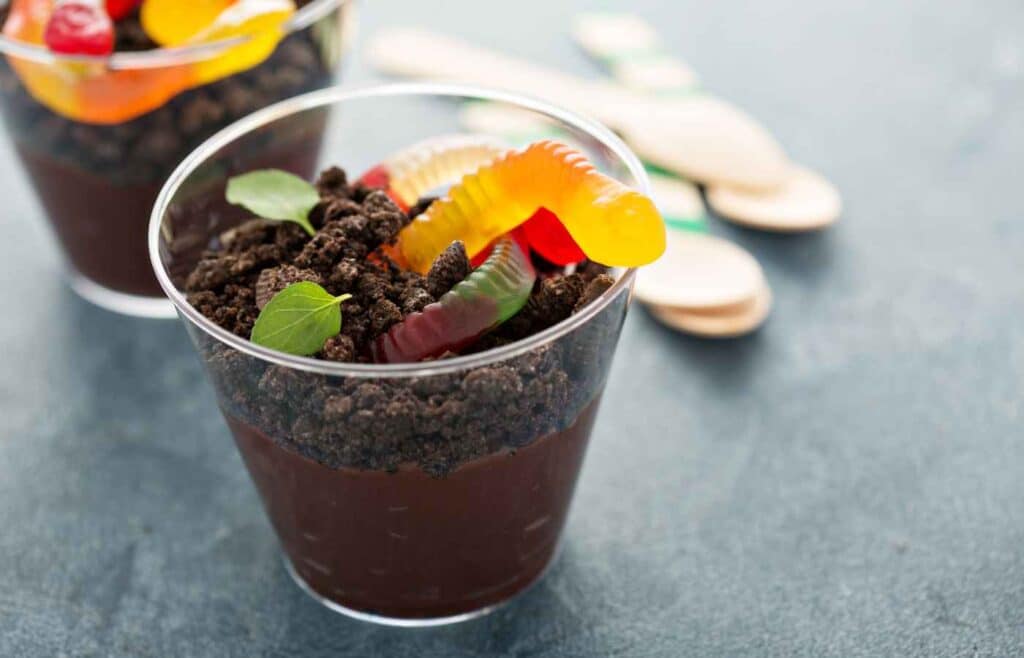 Chocolate pudding topped with crushed chocolate cookies and garnished with gummy worms