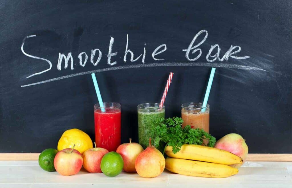 Smoothie station with three glass of different smoothies with fruit displays