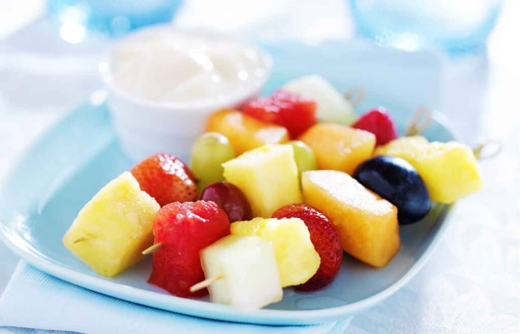 Three pieces of fruit kabobs made up of apples, strawberries, pineapples and blueberries