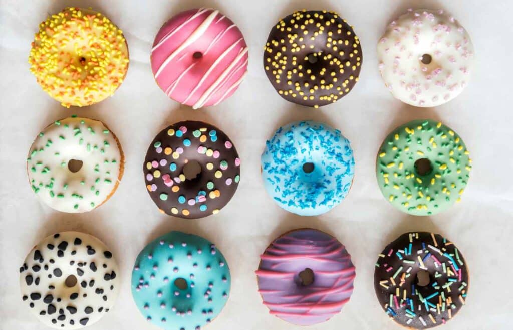 Twelve pieces of assorted glazed donuts placed side by side  
