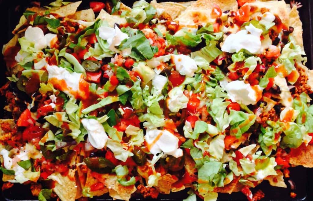 Plate of nachoss with hot sauce, slices of cheese, cabbage and chips for a child's birthday bash