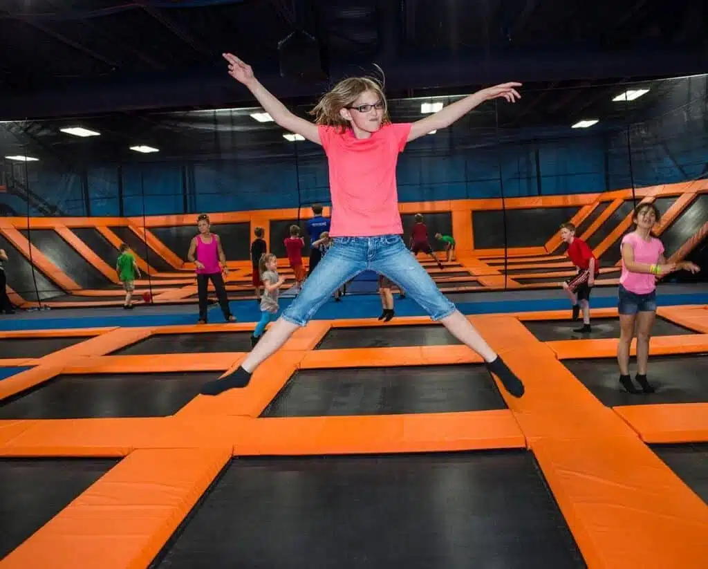 Kids jump across interconnected orange-and-black trampolines 