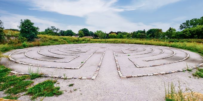 Wide angle view of the stone labyrinth in Hartung Park in Wauwatosa surrounded be green trees and plants.