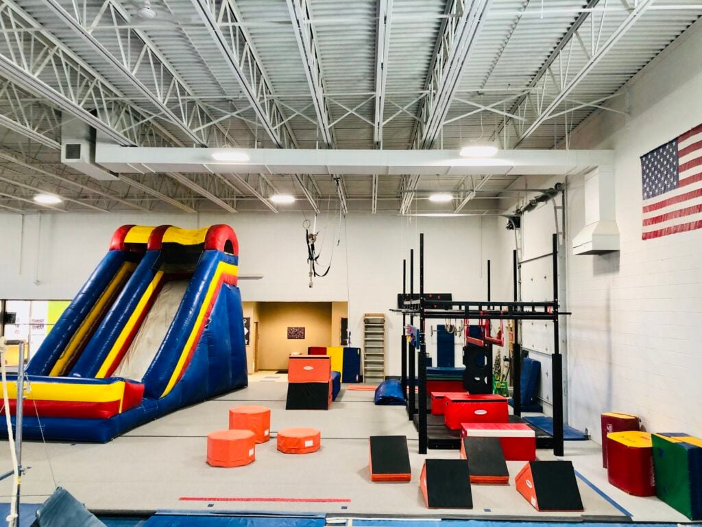 A large inflatable slide, balance beams, boxes and an American flag on the wall at the LaFleur's Gymnastics.