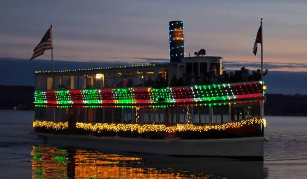 Revelers riding the Lake Geneva Santa Cruise decorated with Holiday lights at dusk
