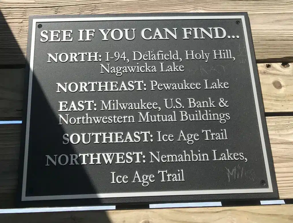 A marker placed on wood boards that indicates the direction of popular areas to visit within Lapham Peak