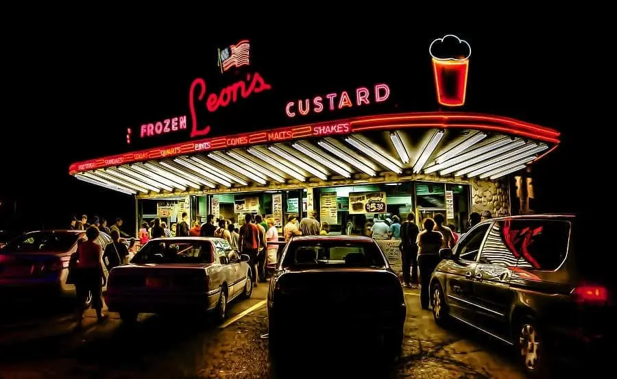 Leon’s Frozen Custard stand in Milwaukee at night with neon lights, cars, and people waiting for frozen custard.