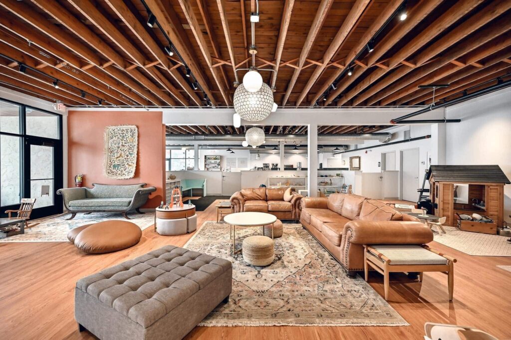 A spacious, modern lounge area with leather sofa, center table and rug with a wooden playhouse in the background.