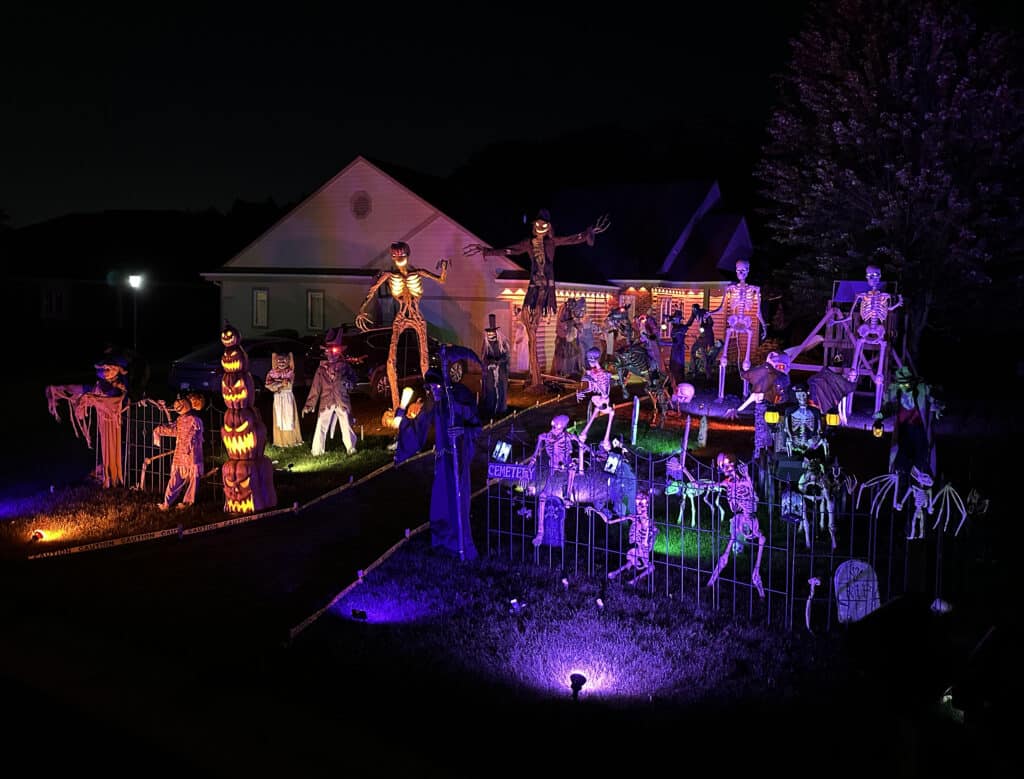 Halloween Display in Menomonee Falls with Skeletons and creepy creatures behind a fence in a  pretend cemetery. The display is called "The Lurking on Lone Creek".