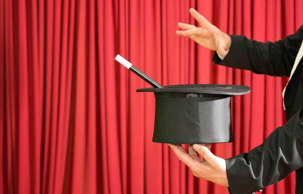 A magician holding a hat and wand during a magic show