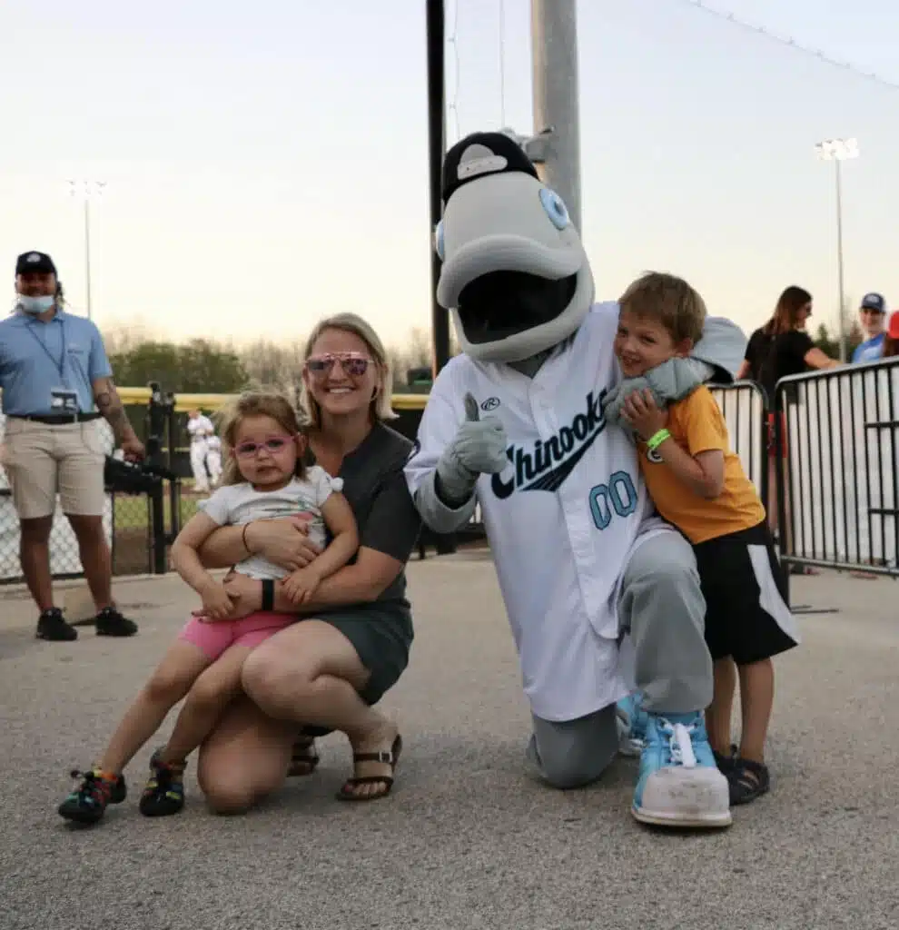 Family poses with Gill the Chinooks mascot near the field.