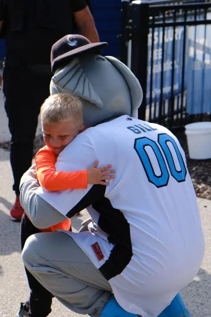 Gill the Chinooks mascot hugs a smiling child before the game.