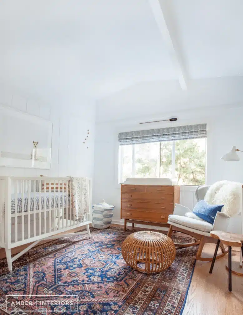 Midcentury modern gender-neutral nursery with wood chest of cabinets and patterned rug