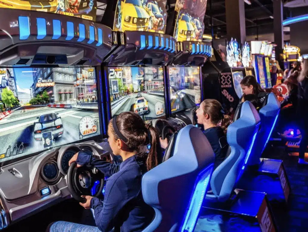 Three teenage girls playing a race simulator arcade game at Dave & Buster's
