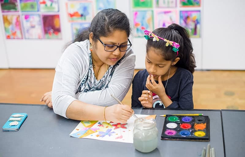 A child learning how to paint from an art teacher.