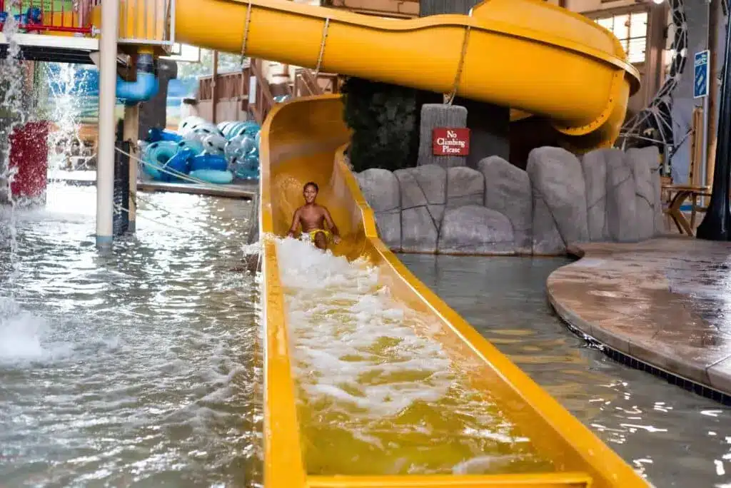 A boy having fun at a yellow pool slide at Springs Water Park at Peewaukee